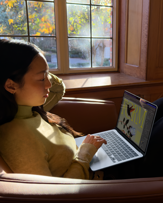 Una persona sentada en una butaca utiliza un MacBook Air