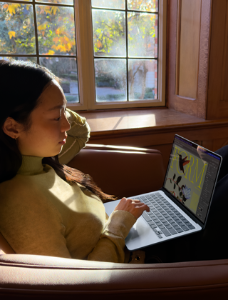 Una persona sentada en una butaca utiliza un MacBook Air