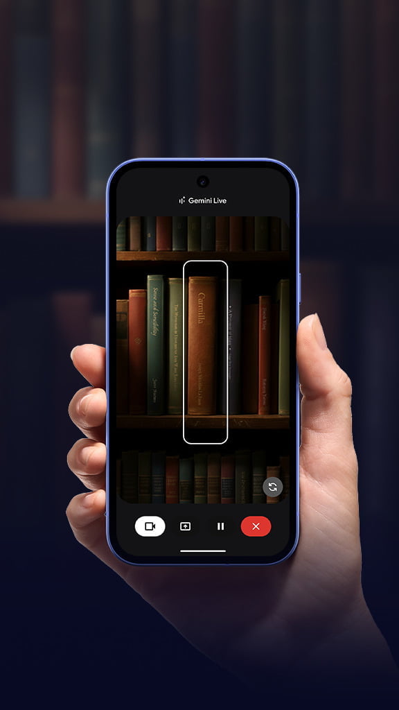 Una mano sosteniendo un dispositivo Pixel en una librería con filas de libros en la pantalla.