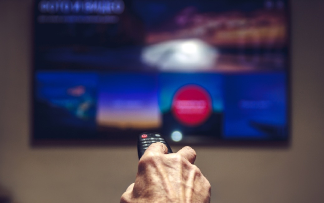 Mano%20sujetando%20un%20mando%20de%20Movistar%20Plus%2B%20frente%20a%20un%20televisor