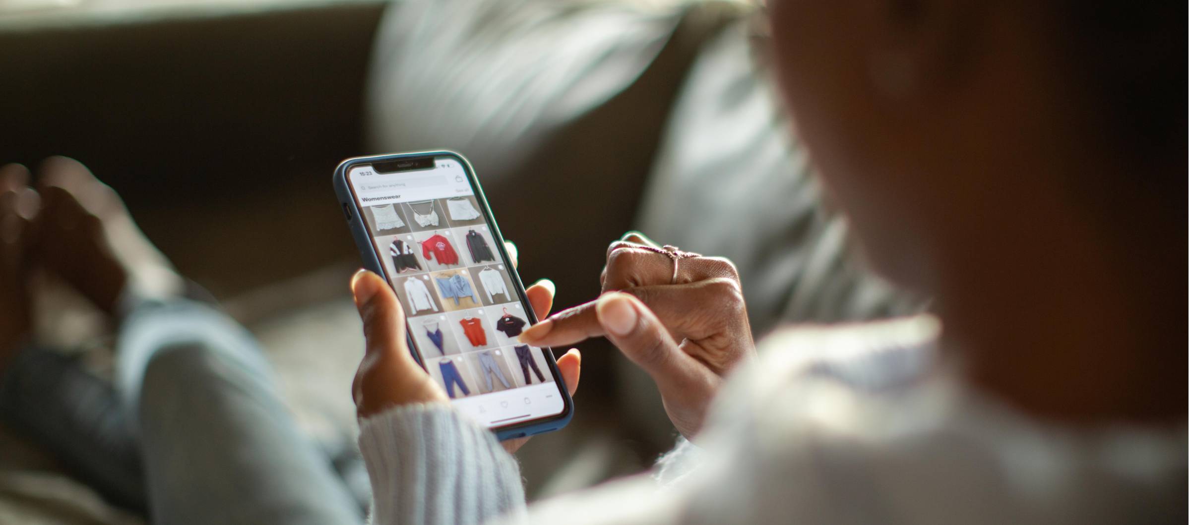 Mujer sentada mirando ropa en un smartphone  